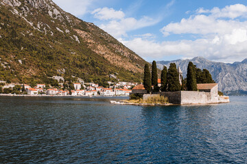 Naklejka premium Outdoor view of Saint George Island in Kotor Bay (Boka Kotorska) near Perast city in Montenegro, sea shore and blue sky in sunny day. Unesco world heritage. Europe travel site. Vacation concept