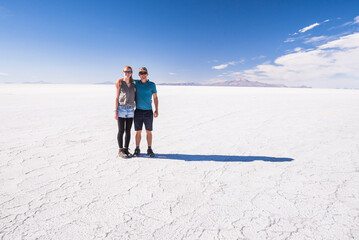 Young tourist couple on vacation while traveling on a gap year, experiencing the amazing, unique landscape of Uyuni Salt Flats (Salar de Uyuni), Uyuni, Bolivia, South America