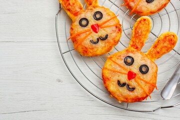 Selective focus on mini easter bunny pizza on cake rake with white wood background.Art food idea...