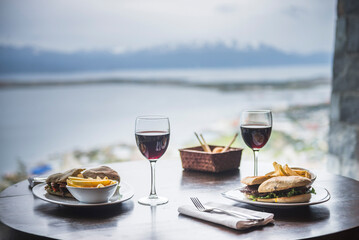 Delicious lunch with red wine at a table at a restaurant with amazing views of the Andes Mountains, Ushuaia, Tierra del Fuego, Patagonia, Argentina, South America - obrazy, fototapety, plakaty