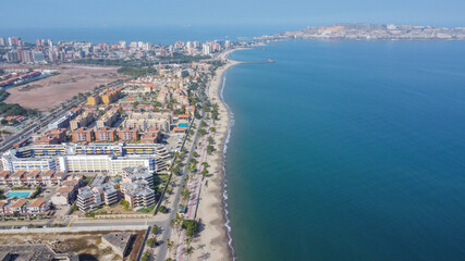 Aerial photos from a drone to a beach in Venezuela, where you can see beaches, residential areas, roads, trees, palms, sand, blue sky, residential hill, pools, roads, waves. © manuel
