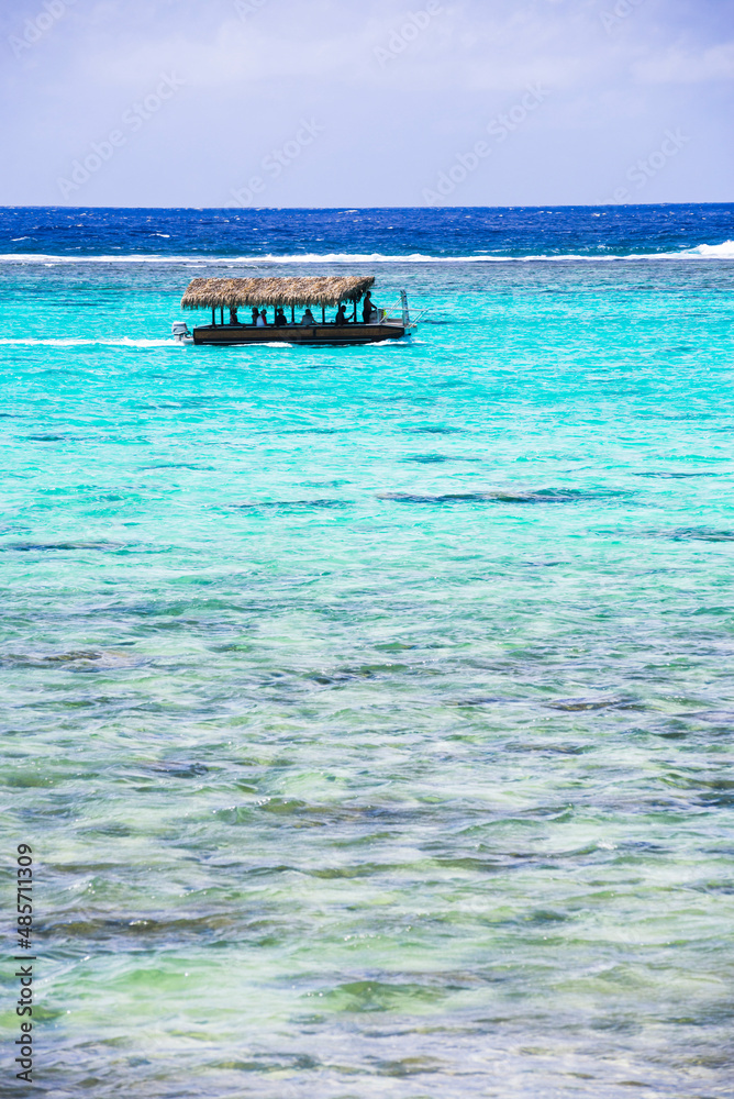 Wall mural Tourist boat trip on a summer vacation to the tropical island of Rarotonga in the perfect crystal clear blue water of Muri Lagoon, Pacific Ocean, background with copy space