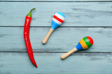 Hot chili pepper and Mexican maracas on blue wooden background