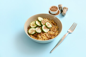 Bowl with tasty oatmeal, flax seeds and cucumber on color background