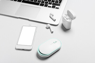 Mobile phone, laptop, earphones and PC mouse on white background