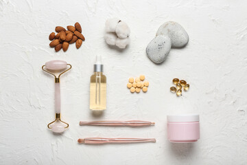 Fototapeta na wymiar Composition with bottle of essential oil, pills, makeup supplies, jar of cream and almond nuts on light background