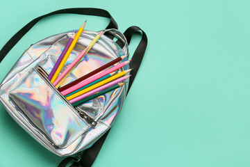 Stylish backpack and pencils on color background