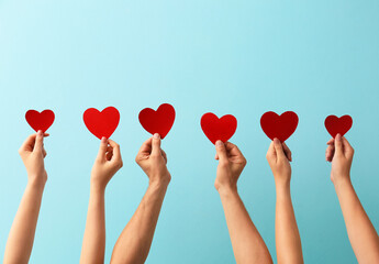 Male and female hands with red paper hearts on color background. Donation concept