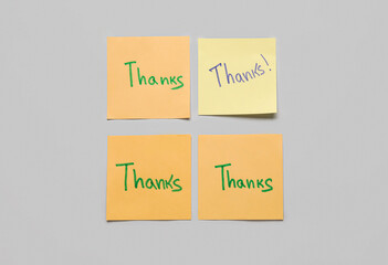 Sticky notes with word THANKS on grey background