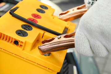 Male mechanic charging car battery, closeup