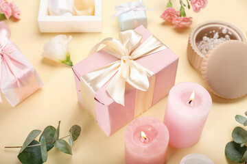 Beautiful composition with flowers, candles and gift boxes on yellow background