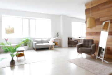 Blurred view of light living room with mirror and stylish furniture