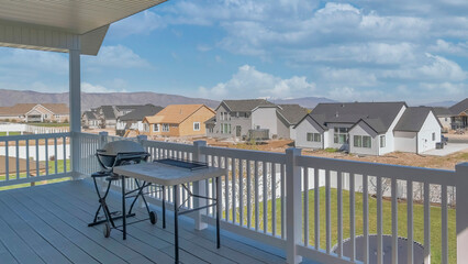 Panorama White puffy clouds View deck of a house with wooden planks flooring and two barbecu