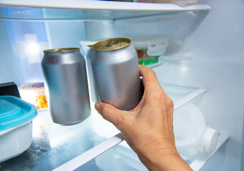 hand picking beer can from refrigerator