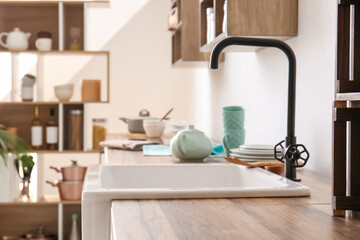 Wooden table top and sink near light wall in kitchen