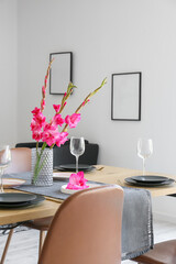 Beautiful table setting and vase with Gladiolus flowers in dining room