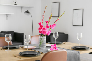 Stylish table setting and vase with Gladiolus flowers in dining room - obrazy, fototapety, plakaty