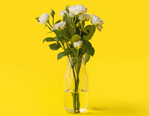 Vase with bouquet of beautiful roses on yellow background