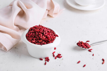 Bowl with dried barberries on light background