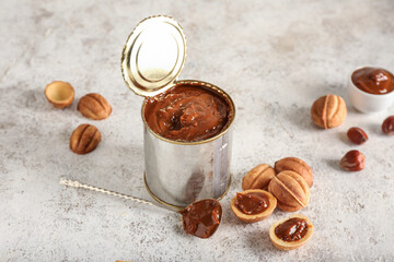 Obraz na płótnie Canvas Tin can with boiled condensed milk and walnut shaped cookies on light background