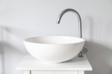 Small table with white sink near light wall