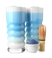 Glasses of blue matcha latte, powder and chasen on white background