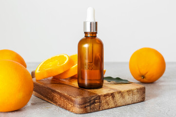 Bottle of essential oil and fresh oranges on light background, closeup