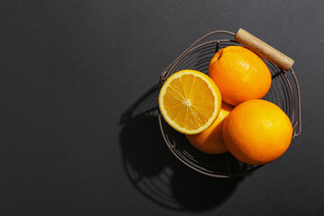 Basket with fresh oranges on dark background