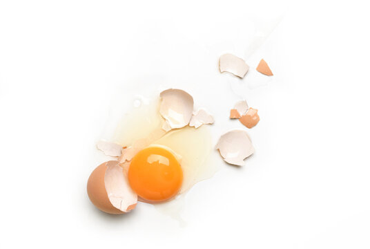 Flat lay of splattered broken egg on white background.