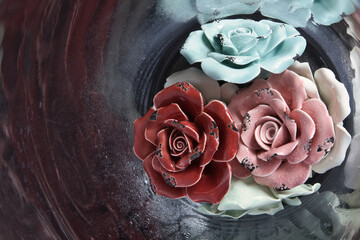 The colorful ceramic roses in glass vase with waterdrops