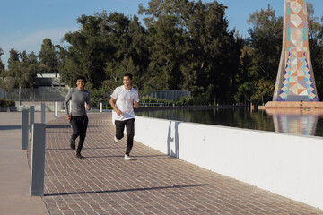 two young male runner friends training together in the park in the middle of nature, enjoying time together and exercise