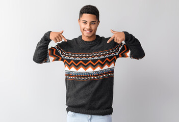 Handsome African-American guy in knitted sweater on light background