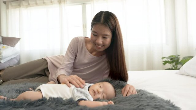 4k, A newborn, 2 month old Asian baby is sleeping on the carpet. with his mother lulling him to sleep beside you with warmth