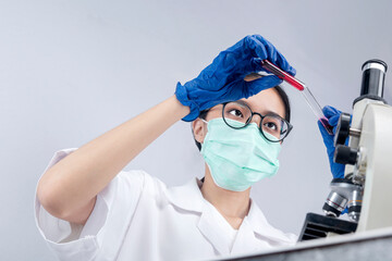 Asian researcher woman with face mask and glasses holding medical tube