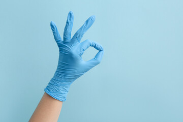 Woman in medical glove showing OK on blue background