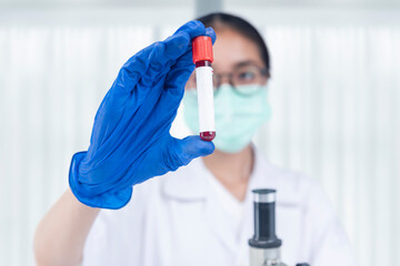Obraz premium Asian researcher woman with face mask and glasses holding medical tube