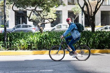 Young man touring a city street on a bicycle looking at camera