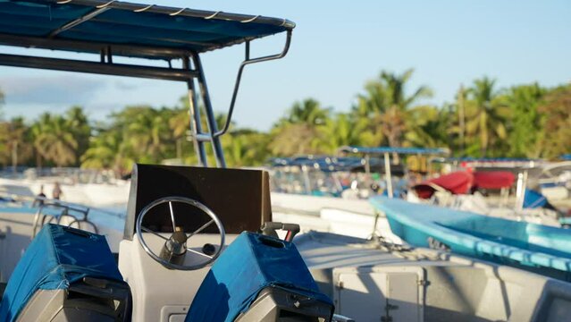 Closeup of a motor boat steering wheel in the port. Many tourist yachts in the back background