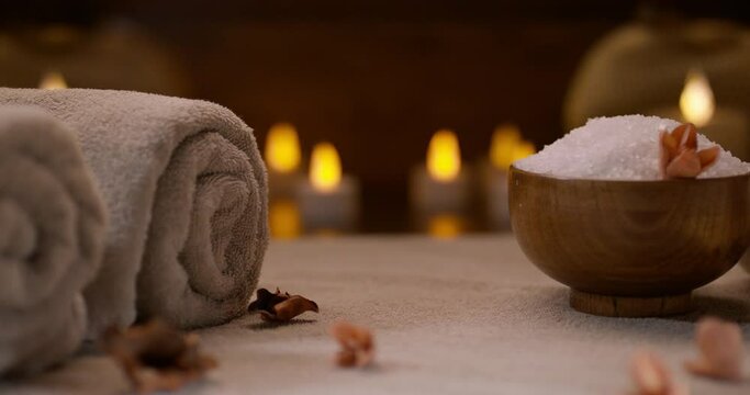 Dried flowers laying on table. Composition of bath salt, hot towels and candle lights on background. Spa, bodycare concept 4k footage