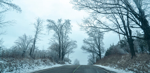 Driving through town on a cold winters day with trees covered in snow