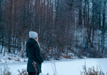 Fototapeta na wymiar Woman stopping to take in the view in a forest on a cold winters day