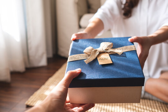 Closeup image of a young couple giving and receiving a gift box to each other