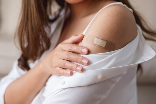 Closeup image of a young woman with adhesive bandage, medical plaster, band aid on her shoulder for vaccination concept