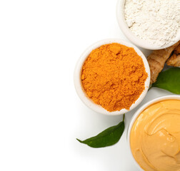 Bowls with turmeric mask and powder on white background