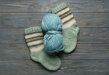 Fototapeta na wymiar Pair of knitted socks, yarn and needles on dark wooden background