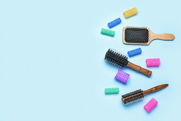 Different hair brushes and curlers on blue background