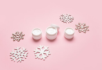 Obraz na płótnie Canvas Jars with cream and snowflakes on color background