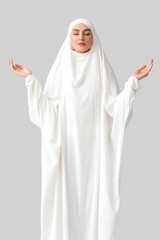 Muslim woman praying on light background