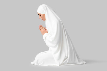 Muslim woman praying on light background