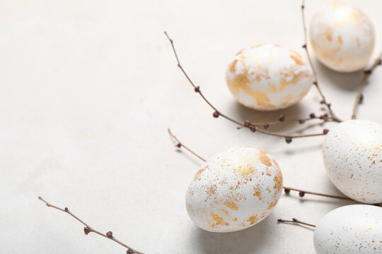 Beautiful Easter eggs and tree branches on light background, closeup